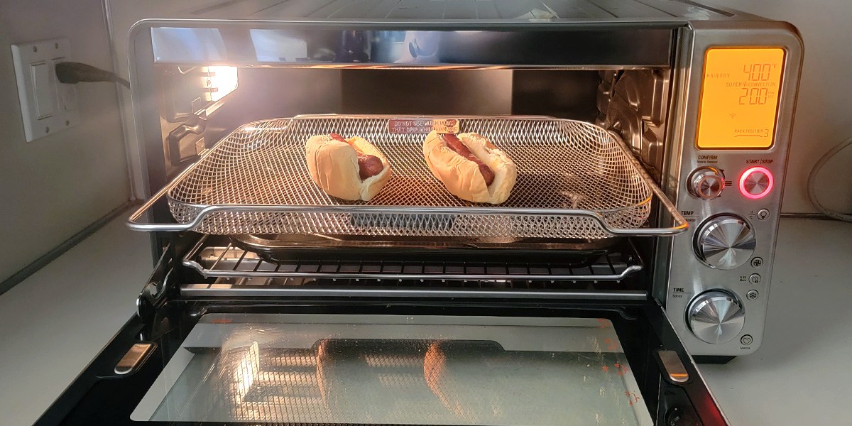 Air fryer with hot dogs cooking inside
